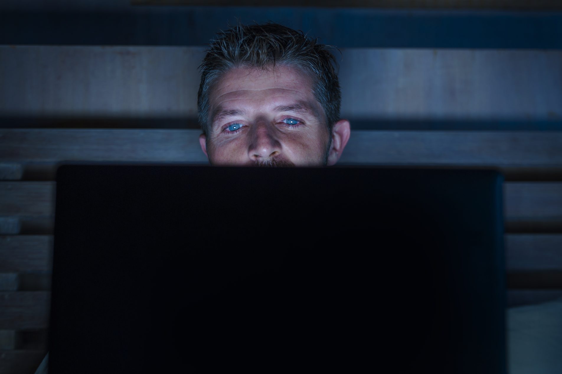 A man alone at a screen in a darkened room